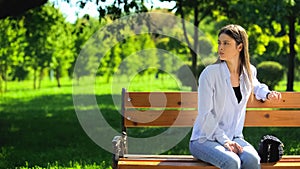 Young female waiting in park sitting on bench, appointment punctuality, time