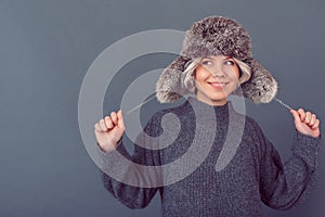 Giovane donna grigio un maglione una foto sul grigio logorante pelliccia un cappello 