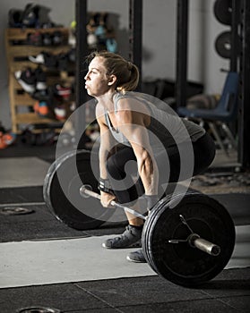 Young female weight lifter preparing for heavy barbell lift