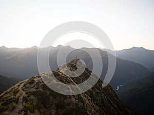 Young female woman hiking along remote alpine mountain ridge path, Brewster Hut Haast Valley, Southern Alps New Zealand