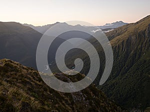 Young female woman hiking along remote alpine mountain ridge path, Brewster Hut Haast Valley, Southern Alps New Zealand