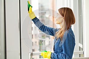 Young female worker cleaning office in yellow protective gloves