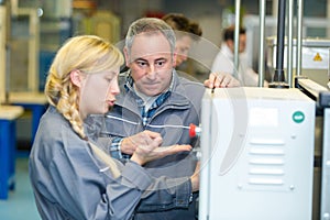 young female worker in discussion with supervisor before machinery controls