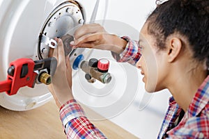 young female worker installing electric boiler at bathroom