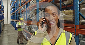 Young female worker using smartphone in a warehouse