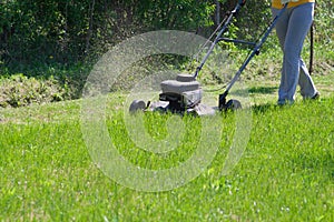 Young female in yard - pushing grass trimming lawnmower