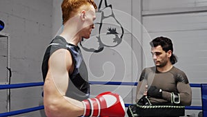 Young fighters are discussing hits during practice on ringside on training in gym.