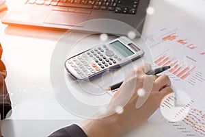 Young finance market analyst working at sunny office on laptop while sitting at white table.Businessman analyze document