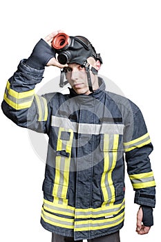 Young firefighter in uniform takes off protective breathing mask from his head