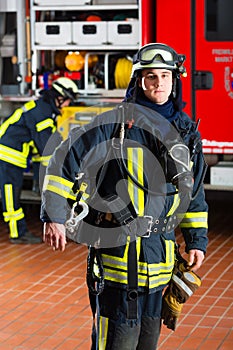 Young fireman in uniform in front of firetruck