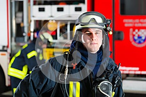 Young fireman in uniform in front of firetruck