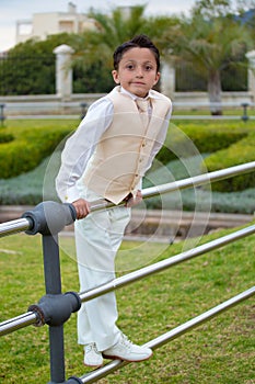 Young First Communion boy leaning on a metal fence