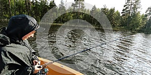 young fisherman is fishing on the boat in a swedish lake