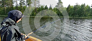 young fisherman is fishing on the boat in a swedish lake