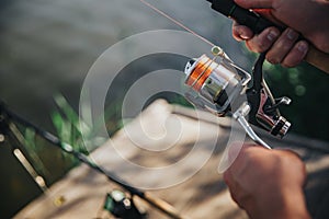 Young fisherman fishing on lake or river. Cut view and close up of man`s hands holding rod and reel using them for