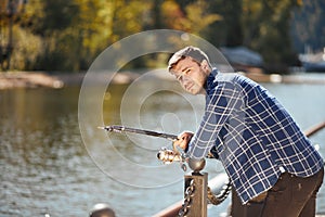 Young fisherman with rod and sunglasses fishing in lake