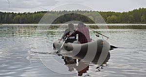 Young fishermen on an inflatable boat on the lake are fishing. Cinematic shot.