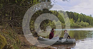 Young fishermen on an inflatable boat on the lake are fishing. Cinematic shot.