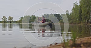 Young fishermen on an inflatable boat on the lake are fishing. Cinematic shot.