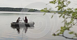 Young fishermen on an inflatable boat on the lake are fishing. Cinematic shot.