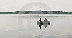 Young fishermen on an inflatable boat on the lake are fishing. Cinematic shot.