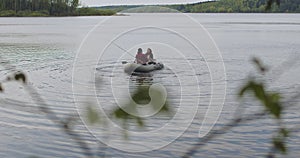 Young fishermen on an inflatable boat on the lake are fishing. Cinematic shot.