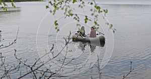 Young fishermen on an inflatable boat on the lake are fishing. Cinematic shot.