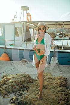 Young fisherwoman stands against background of fishnet and boat