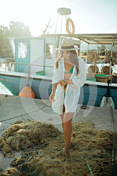 Young fisherwoman stands against background of fishnet and boat