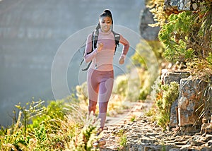 Young fit and active african american woman hiking and jogging through the mountains on a sunny summer day. Black woman