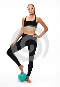 Young fit adult woman doing yoga exercise workout with gymnastics ball