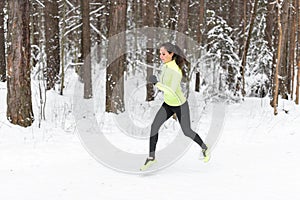 Young fit athlete woman running at forest Sprinting during winter training outside in cold snow weather.