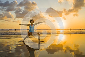 Young fit and attractive sport woman in beach sunset yoga practice workout on wet sun in front of the sea in meditation and relaxa