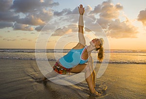 Young fit and attractive sport woman in beach sunset yoga practice workout on wet sun in front of the sea in meditation and relaxa