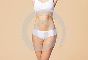 Young, fit and beautiful blond woman in white swimsuit isolated on grey. Healthcare, diet, sport and fitness concept.