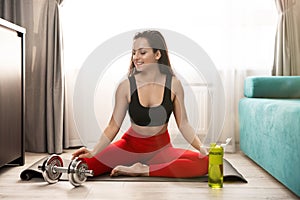 Young fit beautiful woman in sportwear doing everyday warm up exercises with dumbbell on the floor at home, sportive lifestyle