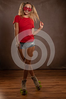 Young fit black woman on roller skates riding outdoors on urban street. Smiling girl with afro hairstyle rollerblading on sunny da