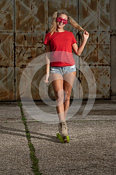 Young fit black woman on roller skates riding outdoors on urban street. Smiling girl with afro hairstyle rollerblading on sunny da