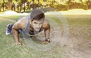 Young fit Caucasian man doing push-ups outdoors on sunny summer day. Fitness and sport lifestyle concept.