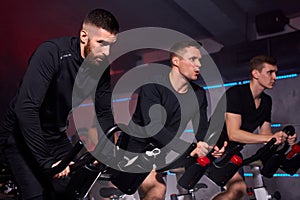 young fit caucasian men exercising and working out in gym, cycling machine bicycle