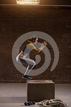 Side view image of fit young woman doing a box jump exercise.