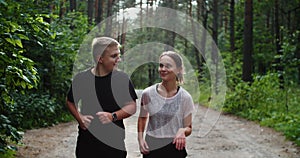 Young fit couple atheltes running on running road in a forest. Check the data on the sports watch. Close-up