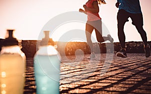 Young fit couple jogging at sunset outdoor - Sporty people doing run workout session next the sea