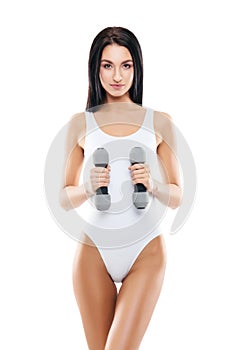 Young and fit girl pumping a dumbbells. Woman in sporty swimsuit. Sport, fitness and healthy lifestyle concept.
