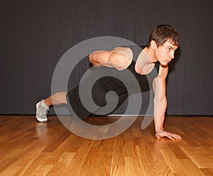 Young fit guy doing exercise in gym