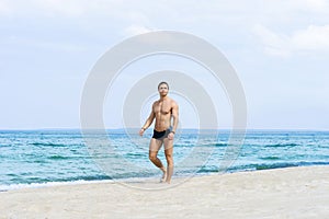 Young, fit handsome man on a summer beach