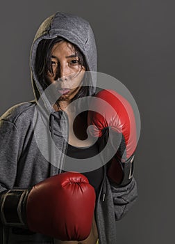 Young fit and healthy Asian Korean boxer woman in fitness top hoodie and boxing gloves posing cool badass attitude angry and defia