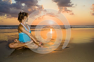 Young fit and healthy attractive woman practicing fitness and yoga in beautiful sunset beach in meditation and relaxation concept