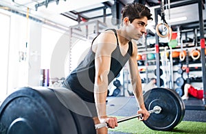 Young fit hispanic man in gym lifting heavy barbell