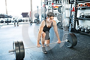 Young fit hispanic man in gym lifting heavy barbell